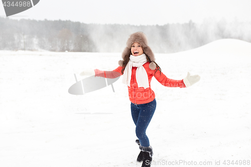 Image of happy woman in winter fur hat having fun outdoors