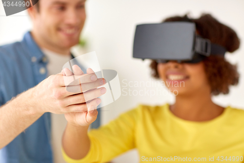 Image of happy couple with virtual reality headset at home