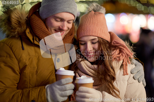 Image of happy couple with coffee over christmas lights