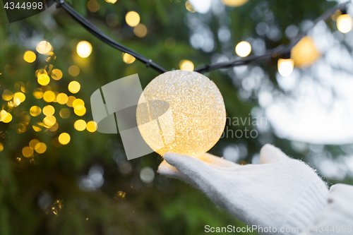 Image of close up of hand with christmas tree garland bulb