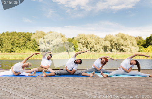 Image of group of people making yoga exercises outdoors