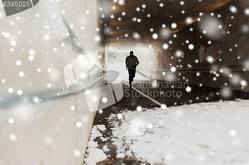 Image of man running along subway tunnel in winter