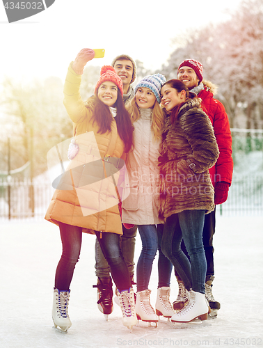 Image of happy friends with smartphone on ice skating rink