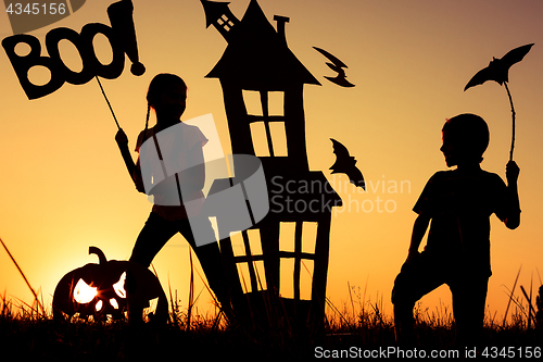 Image of Happy brother and  sister playing outdoors at the sunset time.