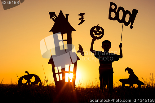 Image of Happy little boy playing outdoors at the sunset time.