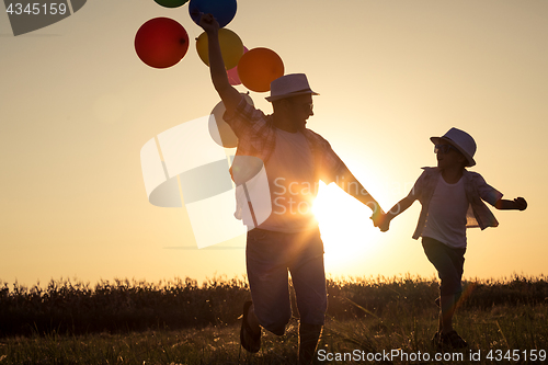 Image of Father and son running on the road at the sunset time.