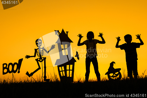 Image of Happy brother and  sister playing outdoors at the sunset time.