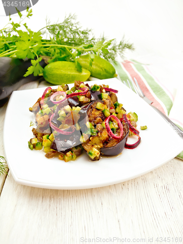 Image of Salad from eggplant and cucumber with onion in plate on board