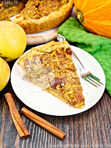 Image of Pie with pumpkin and apples in plate on dark board