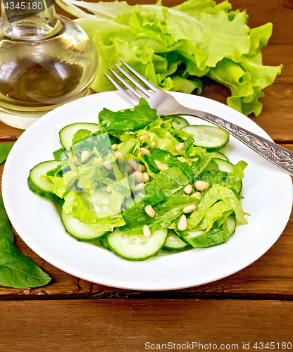 Image of Salad from spinach and cucumbers with fork on wooden table