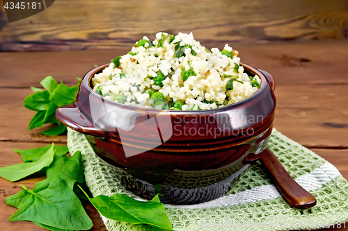 Image of Couscous with spinach and green peas in bowl on wooden board