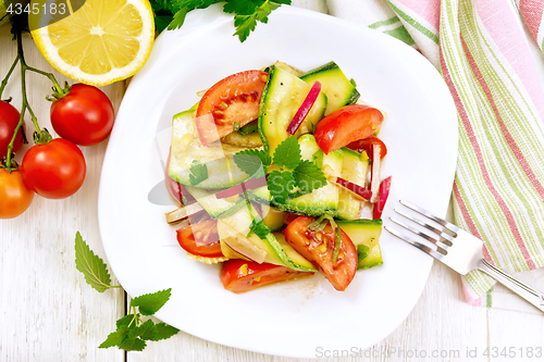 Image of Salad with zucchini and tomato in plate on board top