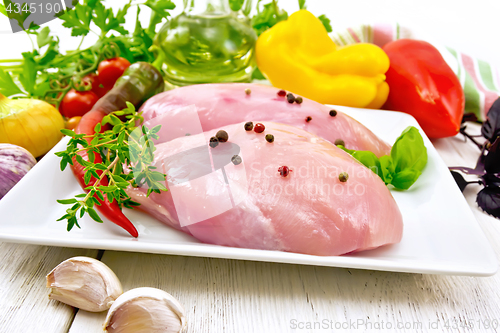 Image of Chicken breast raw in plate with vegetables on board