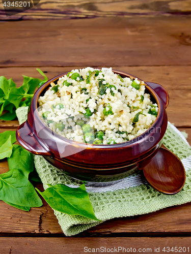 Image of Couscous with spinach in bowl on wooden board