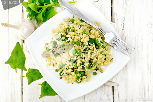 Image of Couscous with spinach in plate on board top