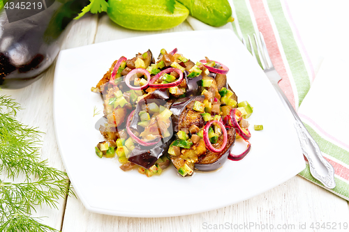 Image of Salad from eggplant and cucumber with red onion in plate on boar