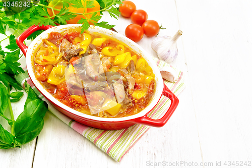 Image of Ragout of meat and vegetables in red brazier on board