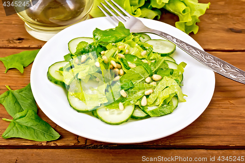 Image of Salad from spinach and cucumbers with cedar nuts on table