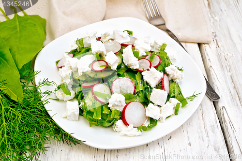 Image of Salad with cheese and radishes in plate on light board