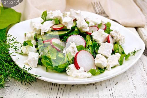 Image of Salad with cheese and radishes in plate on board