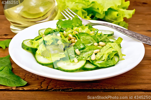 Image of Salad from spinach and cucumber with fork on board
