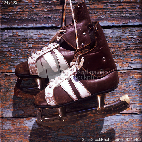 Image of vintage pair of mens  ice skates hanging on a wooden wall