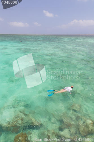 Image of Woman snorkeling in clear shallow sea of tropical lagoon with turquoise blue water.