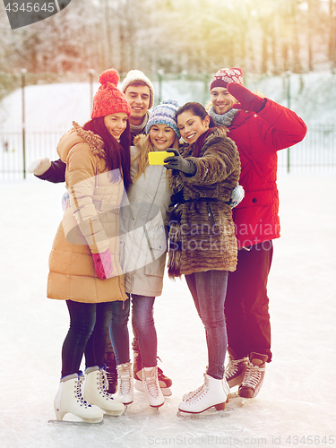 Image of happy friends with smartphone on ice skating rink