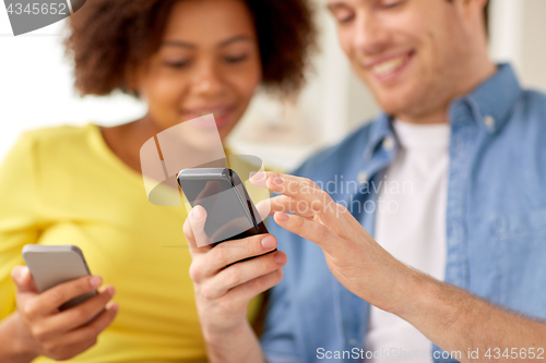 Image of happy couple with smartphones at home