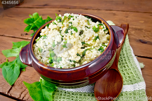 Image of Couscous with spinach in bowl on board