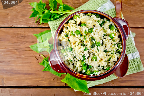 Image of Couscous with spinach in bowl on board top