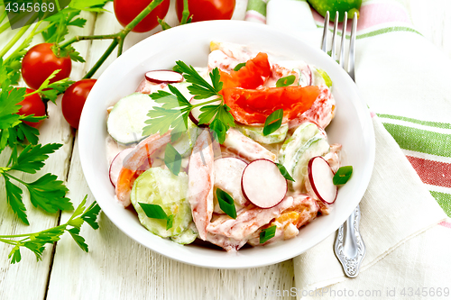 Image of Salad from fresh vegetables with greens in plate on light board