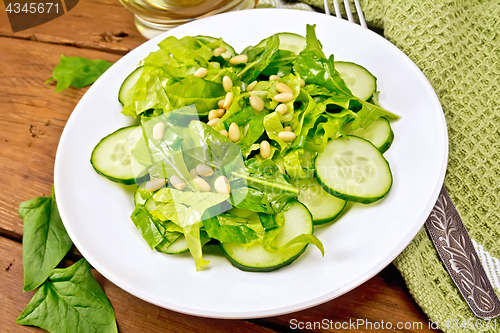 Image of Salad from spinach and cucumbers with fork on table