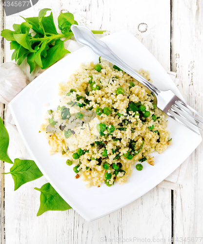 Image of Couscous with spinach and green peas in plate on board top