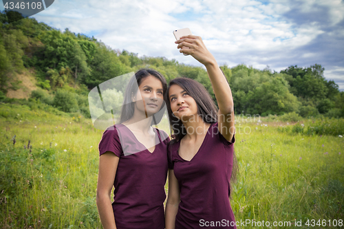 Image of Beautiful young twins girls doing selfie