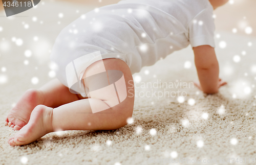 Image of little baby in diaper crawling on floor