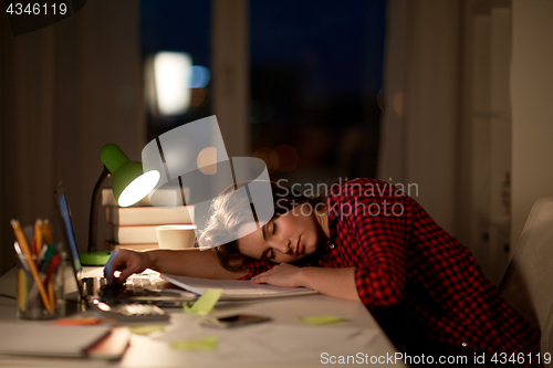 Image of student or woman sleeping on table at night home