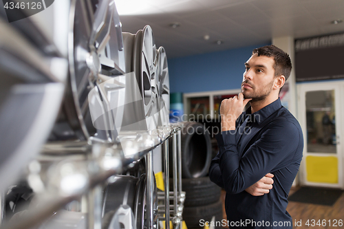 Image of male customer choosing wheel rims at car service