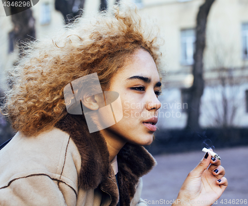 Image of young pretty girl teenage outside smoking cigarette, looking lik