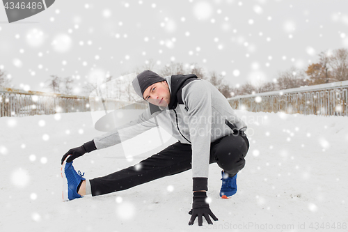 Image of man exercising and stretching leg on winter bridge