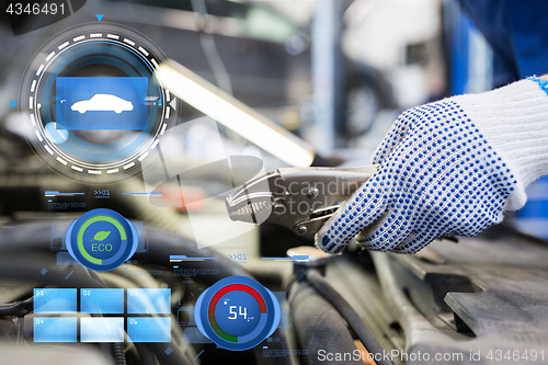 Image of mechanic man with pliers repairing car at workshop