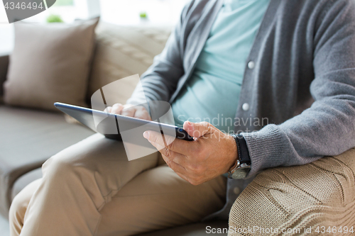 Image of close up of senior man with tablet pc on sofa