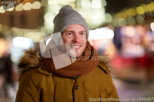 Image of happy young man over christmas lights in winter