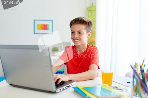 Image of student boy typing on laptop computer at home