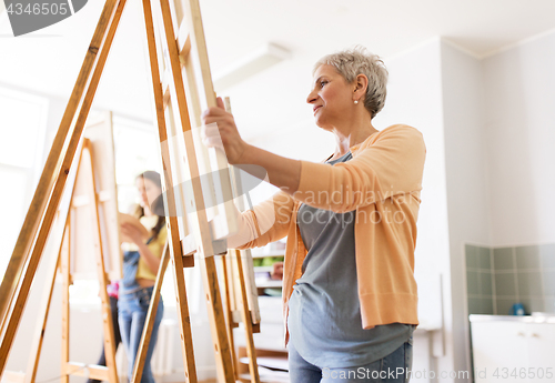 Image of woman artist with easel drawing at art school