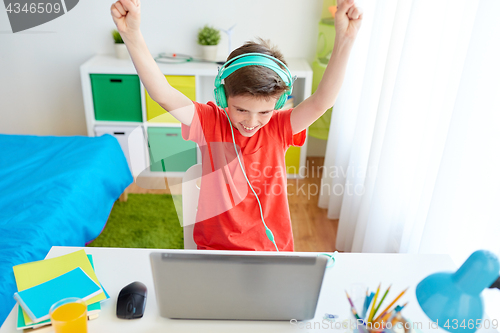 Image of boy with headphones playing video game on laptop