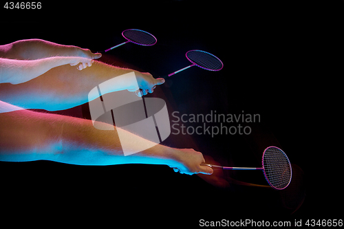 Image of The hands of young man playing badminton over black background