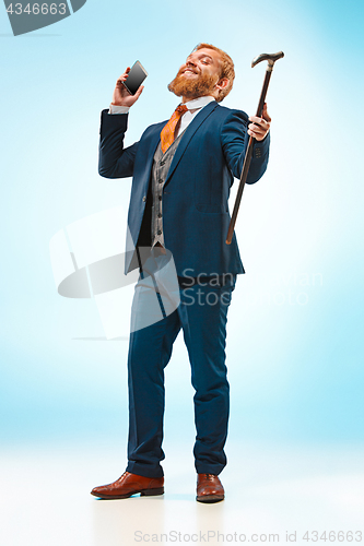 Image of The barded man in a suit holding cane.