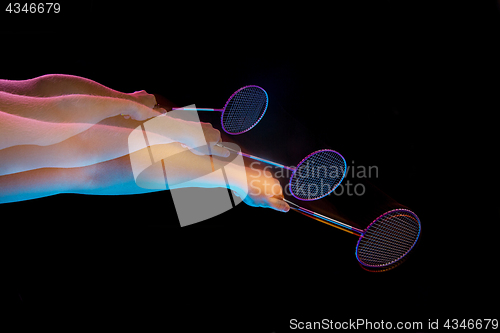 Image of The hands of young man playing badminton over black background