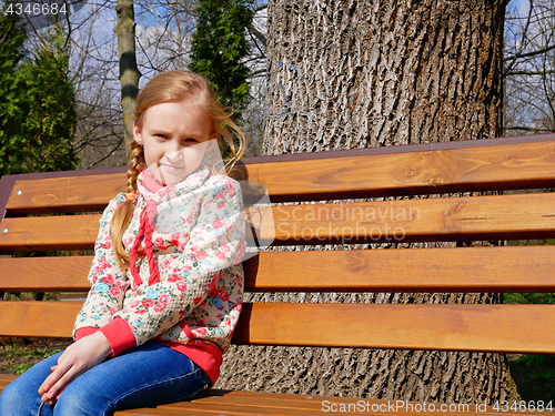 Image of Small girl sits on the bench
